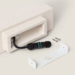 Applique murale extérieure en ciment texturé sable, forme rectangulaire, câblage et support de fixation visibles