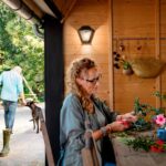 Applique murale extérieure noire en métal type lanterne à verre, montée sur mur bois, éclairage chaud