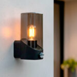 Applique murale extérieure noire en métal avec abat-jour cylindrique en verre fumé et détecteur