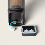 Applique murale extérieure noire avec diffuseur cylindrique, boîtier de connexion ouvert et fils visibles (vert-jaune, bleu)