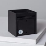 Applique murale carrée noire en métal avec petit élément circulaire sur la façade