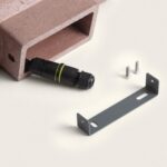 Applique murale en ciment rouge avec connecteur étanche noir, support métallique de fixation et vis