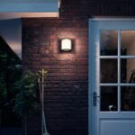 Applique murale extérieure noire à diffuseur opalin, fixation murale sur brique, éclairage doux près d'une porte