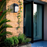 Applique murale extérieure à diffuseur blanc opalin, cadre gris foncé métallique, forme rectangulaire arrondie, fixation murale verticale