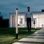 Balise extérieure LED noire à diffuseur vertical, montage au sol près d'une allée