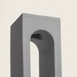 Balise extérieure en ciment gris, forme rectangulaire avec arche et LED intégrée orientée vers le bas