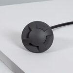 Balise encastrable de sol noire, finition mate, forme ronde avec découpes croisées et câble d'alimentation