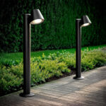 Balise sur pied noire en métal, tête conique orientée, fixation au sol sur platine