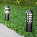 Balise sur pied noire en métal avec diffuseur blanc et lames horizontales, installation en bordure de pelouse