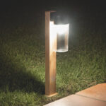 Balise sur pied bois clair avec diffuseur cylindrique en verre transparent et chapeau inox pour éclairage extérieur