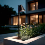 Balise sur pied métal noir mat, abat-jour conique, montée sur piquet dans jardinière