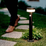 Balise solaire sur pied noire en aluminium, corps cylindrique et diffuseur LED circulaire, installation au sol