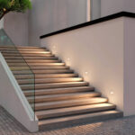 Balise encastrée murale ronde blanche, éclairage blanc chaud le long d'un escalier extérieur