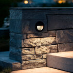 Balise encastrable murale ronde noire, lumière blanc chaud, montée dans un mur en pierre