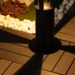Balise sur pied cylindrique noire en métal, éclairage LED chaud, fixée sur terrasse en bois