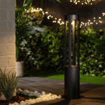 Balise sur pied noire en métal cylindrique avec ouvertures verticales pour éclairage extérieur solaire