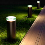 Câble d'extension noir pour éclairage extérieur reliant bornes lumineuses cylindriques posées sur pelouse