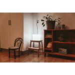 Lampe cube nomade blanche à diffuseur opalin, posée sur un tabouret et branchée par câble