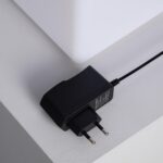 Chargeur secteur noir à prise européenne posé près d'un cube LED blanc