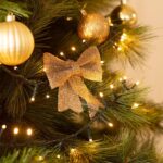 Guirlande LED à câble noir avec petites lampes blanc chaud sur sapin, entourée d'ornements dorés