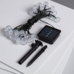 Guirlande solaire LED 30 boules transparentes, câble noir, panneau solaire et piquet de fixation