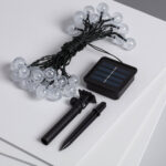 Guirlande LED solaire avec boules transparentes, câble noir et panneau solaire avec piquet d'installation