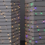 Guirlande LED extérieure sur câble noir, enroulée autour de colonnes, lampes blanc chaud et multicolores