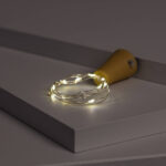 Guirlande LED fil de fer blanc chaud enroulée autour d’un bouchon jaune pour bouteille