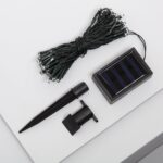 Guirlande LED solaire sur câble vert avec petites ampoules, panneau solaire et piquet de fixation