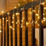 Guirlande LED style gouttes blanc chaud accrochée à une rambarde métallique extérieure