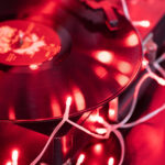Guirlande LED rouge à fil blanc posée autour d'un disque vinyle