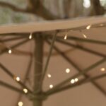 Guirlande LED blanc chaud enroulée autour de l'armature de parasol