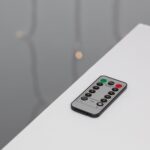 Télécommande grise et noire pour guirlande LED extérieure, boutons rouges et verts visibles