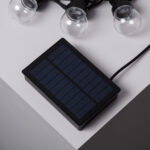 Guirlande solaire avec ampoules LED transparentes et panneau solaire rectangulaire noir, câble visible