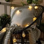 Guirlande LED extérieure à ampoules sphériques jaune chaud drapée sur un fauteuil