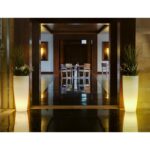 Jardinière LED extérieure blanche translucide à lumière chaude, forme tubulaire conique sur pied avec plantes