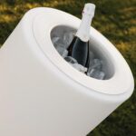 Jardinière cylindrique blanche utilisée comme seau à glace avec cuve ronde intégrée contenant bouteille et glaçons