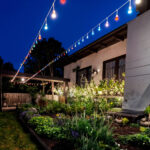 Guirlande lumineuse extérieure blanche avec ampoules LED multicolores suspendue au-dessus d'un jardin