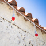 Guirlande guinguette blanche avec ampoules rouges suspendues sous toit