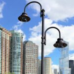 Lampadaire extérieur en métal noir à bras coudé et abat-jour en cloche, montage sur mât urbain