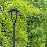 Lampadaire extérieur noir en métal, tête ronde plate avec diffuseur opalin, mât élancé pour éclairage public