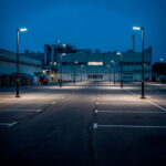 Lampadaire LED extérieur noir sur mât avec tête rectangulaire éclairant un parking urbain