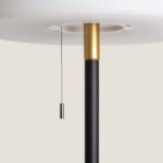 Lampadaire noir à mât cylindrique avec embout doré et cordon d'allumage en métal