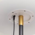 Lampadaire solaire extérieur noir en tube métallique, embout doré et platine de fixation blanche avec câbles visibles