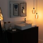 Suspension en verre texturé avec câble noir, abat-jour cylindrique transparent suspendu au-dessus d’un lavabo