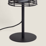 Lampe à poser noire en métal, base ronde, tige cylindrique et abat-jour grillagé