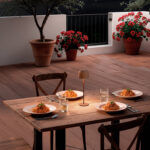 Lampe à poser extérieure portative en aluminium couleur rouille, lumière chaude sur table de terrasse