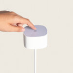 Lampe à poser blanche forme carrée arrondie avec bouton tactile sur le dessus, montée sur tige fine