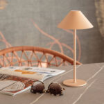 Lampe à poser beige avec abat-jour conique, tige fine et socle rond sur table