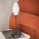 Lampe à poser, abat-jour ovoïde blanc texturé, pied et base métal noir, posée sur table